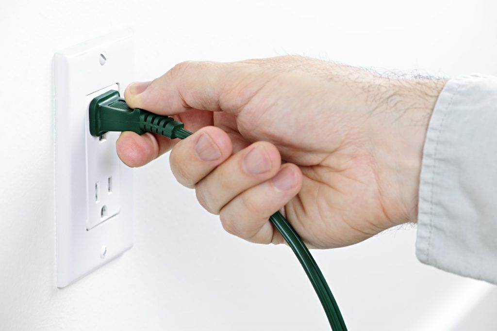 Hand removing plug from outlet
