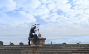 chimney sweep cleaning chimney on rooftop