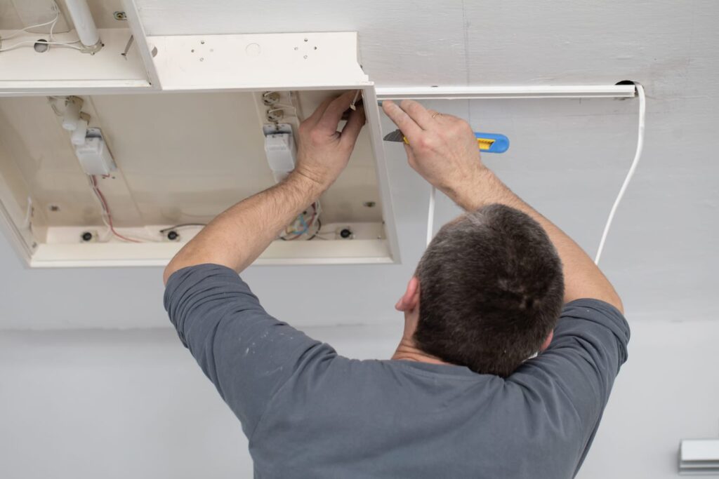 electrician wiring a lighting fitting in ceiling