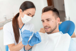 An orthodontist shows an Invisalign aligner to a patient.