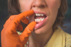 A woman with a malocclusion uses gloves to show her crooked teeth.