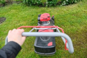 A person mowing the lawn seen from the mower's point of view.