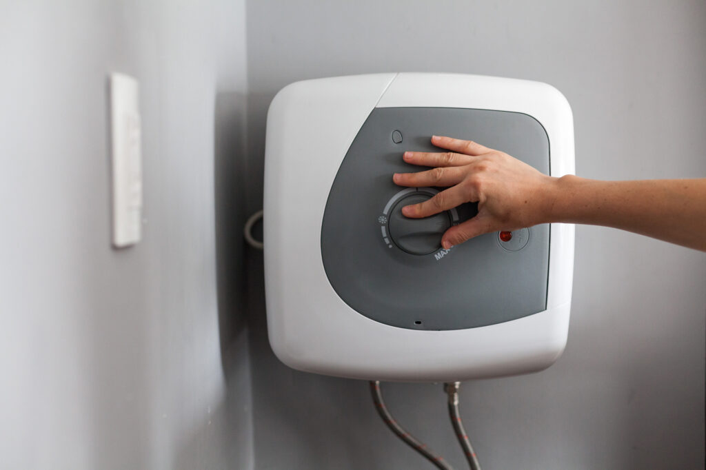 A person adjusts the temperature on a modern electric water heater.