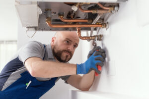 A plumber checks the pipes as he installs a natural gas boiler in a home.