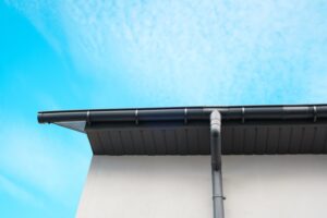 Spouting on the roof of a contemporary home against a bright blue sky.
